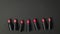 Samples of lipstick bottles randomly stacked on a black background.
