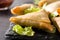 Samsa or samosas with meat and vegetables on black background.