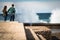 San Sebastian, Spain - March 16, 2018: couple sitting on stone wall admiring scenic huge splash of sea water waves