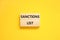 Sanctions list symbol. Wooden blocks with concept words Sanctions list on beautiful yellow background. Business political