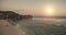 Sand beach with cliff shore of ocean bay aerial. Sunrise above sea waterfront. Sun rise seascape