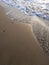 sand beach and sea waves top view. Soft wave and sunny sand shore. Vertical photo.