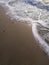 sand beach and sea waves top view. Soft wave and sunny sand shore. Vertical photo.