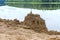 Sand building on the beach, sand castle on the shore of the pond