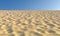 Sand with bumps and fossas under blue sky