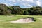 Sand bunkers in front of putting green at golf course