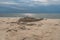 Sand castle on the beach against the background of a pre-sunset summer sky. Summer fun and games