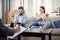 Sand clock at psychologist cabinet with unhappy annoyed caucasian couple having psychologist therapy session on