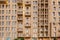 Sand color facade of modern residenial building, with rows of small windows and balconies, front view