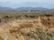 Sand Colored Jagged Cliffs Along the Californa Pacific Coast with Mountains in the Background