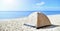 Sand-colored tourist tent on the seashore in the sand. Calm morning sea. camping with a tent at a lonesome beach