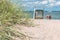 Sand dune with grass and blue colored roofed chairs on sandy beach and blurred kids in Background. Travemunde. Germany