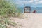 Sand dune with grass and blue colored roofed chairs on sandy beach and blurred kids in Background. Travemunde. Germany