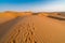 Sand dunes with footprints in them under the blue sky with soft haze on the distant horizon. Lae afternoon in the desert