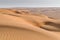 Sand dunes with footprints in them under the blue sky with soft haze on the distant horizon. Lae afternoon in the desert