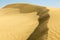 Sand dunes with wind in the desert with blue sky