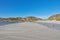 Sand on an empty beach with blue sky copy space. Beautiful landscape of a scenic ocean coastline with rocky Mountains or