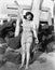 With sand between her toes, a young woman waves on the beach