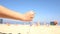 Sand pouring from the hands of a woman on the beach.