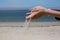 Sand pours through fingers against the sea beach. nature.