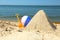 Sand pyramid, colorful ball and plastic shovel on beach