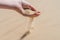 Sand spilling out pouring flow of the hand in the sandy desert dunes on bright sunny day. Transience of time. Selective focus