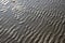 Sand texture. Background with beige fine sand. Sharp lines of waves on sand. Sand surface on the beach, side view.