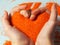 Sand therapy, orange kinetic sand in the shape of a heart in children`s hands