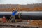 sandblasting of the pipeline weld. A worker with a nozzle processes an oil pipeline. Autumn day