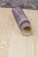 sandpaper twisted into a roll lies on a wooden board. Close-up. There is a tint