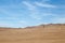 Sands of the desert under bright blue sky with few clouds