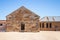 Sandstone brick convict built building with decorative stonework, corrugated iron roof, arched doorway, pebbled courtyard against