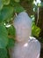 Sandstone Buddha partly hidden behind a Hortensia