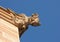 Sandstone gargoyle on church against blue sky