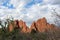 Sandstone rock formations towering above a tree line and backed by cumulus clouds at the Garden of the Gods in Colorado