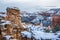 Sandstone tower in beautiful evening light peeking through winter storm clouds after fresh snow