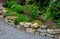 Sandstone walls and stones in a flowerbed in a terraced terrain with stairs. flowering rock gardens and stairs with a gravel surfa