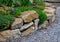Sandstone walls and stones in a flowerbed in a terraced terrain with stairs. flowering rock gardens and stairs with a gravel surfa