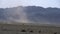 Sandstorm raging in desert, mountains looming in background