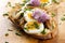 Sandwich with adition of mackerel fish , eggs and edible flowers of chives on wooden table