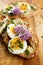 Sandwich with adition of mackerel fish , eggs and edible flowers of chives on wooden table