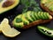 Sandwich with avocado on a dark homemade bread made from fresh sliced avocados on a black stone background. Close-up. Slices of