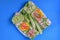 Sandwich with avocado, radish, cucumber, raw ham, pepper and fresh cheese on a blue background, top view