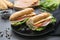 Sandwich with baguette bread, ham, lettuce, tomatoe over dark background. Breakfast or fast food