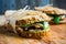 Sandwich with cereal bread, chicken, pesto and cheese on the rustic wooden background