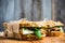 Sandwich with cereal bread, chicken, pesto and cheese on the rustic wooden background
