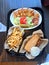 Sandwich, Crinkle Cut Fries and a plate with Fried Shrimp, Lettuce, Pickle, Tomato and Sauce in Container on a Black Plastic Tray