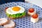 Sandwich with egg, ham, cheese, toast and salad leaves lies on a plate with tomato and dill