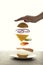 Sandwich floating in the air on a white background. The sandwich rises behind the woman`s hand, the power of levitation