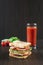A sandwich and a glass of tomato juice on a wooden table